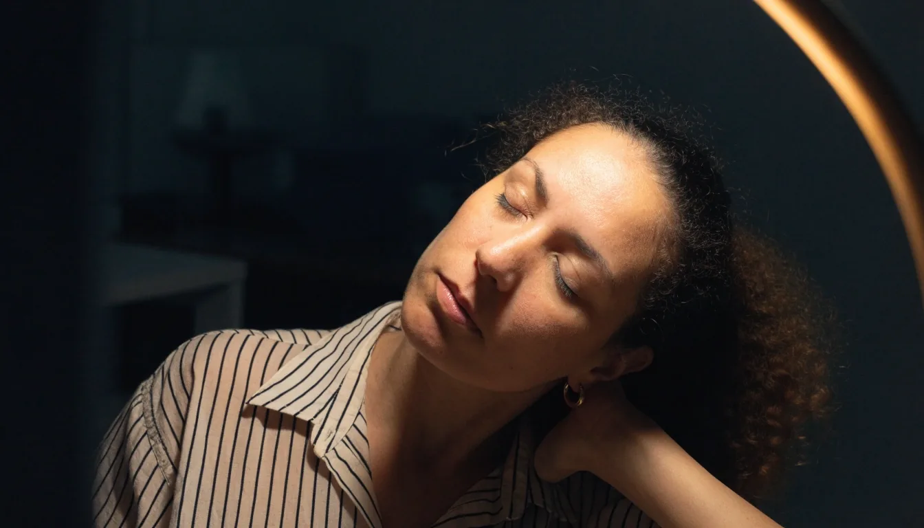 A woman resting a hand at the back of her neck with her eyes closed after a long stretch of screen work